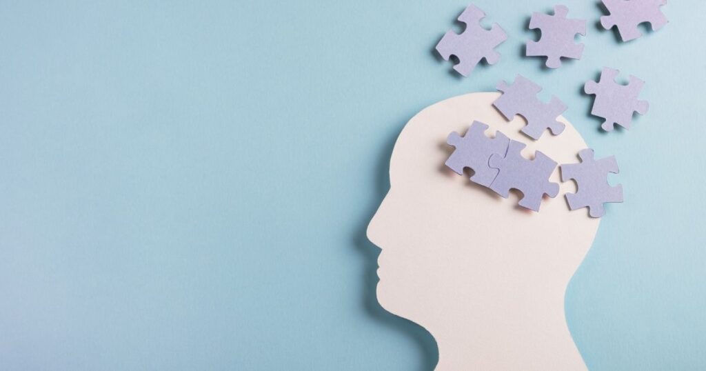 A profile cutout of a person with puzzle pieces shown in the brain area. 