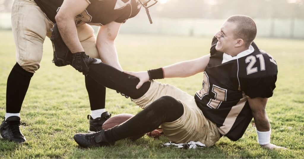 A football player assisting an injured player.